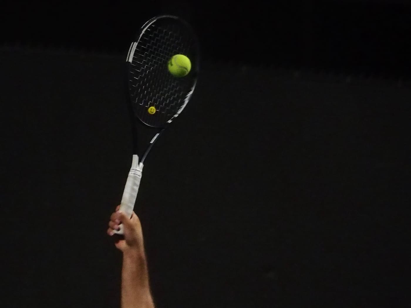 Coach Hayk serving under floodlights during evening practice in Los Angeles
