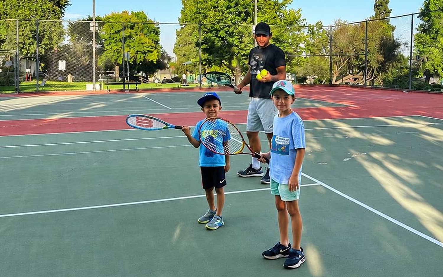 Coach Hayk on court with two young beginners during a kids tennis lesson near Pasadena