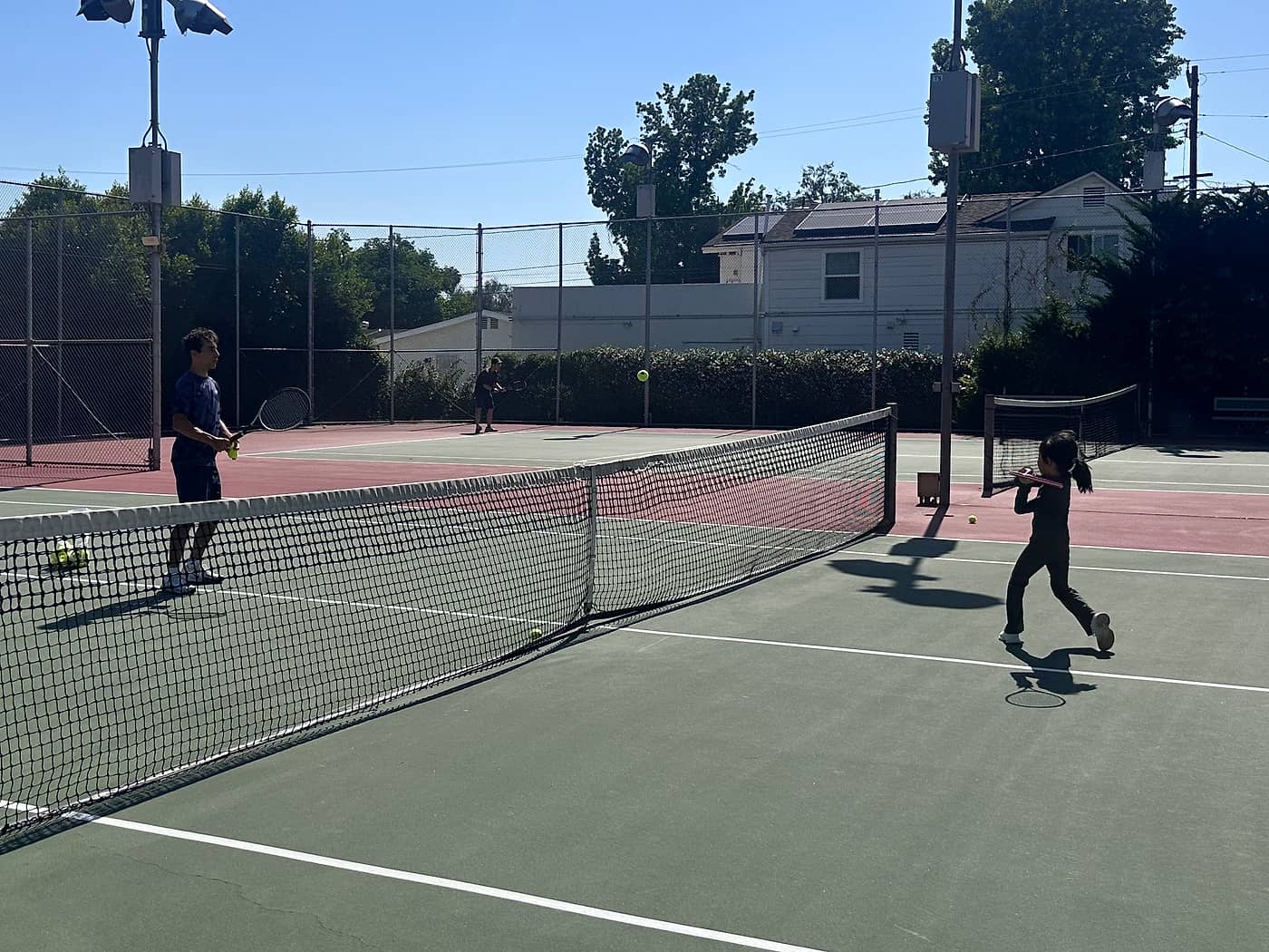 A private junior tennis lesson in progress on a public court near Pasadena, California
