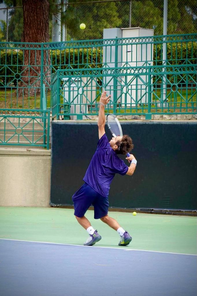 Markos serving on tennis court